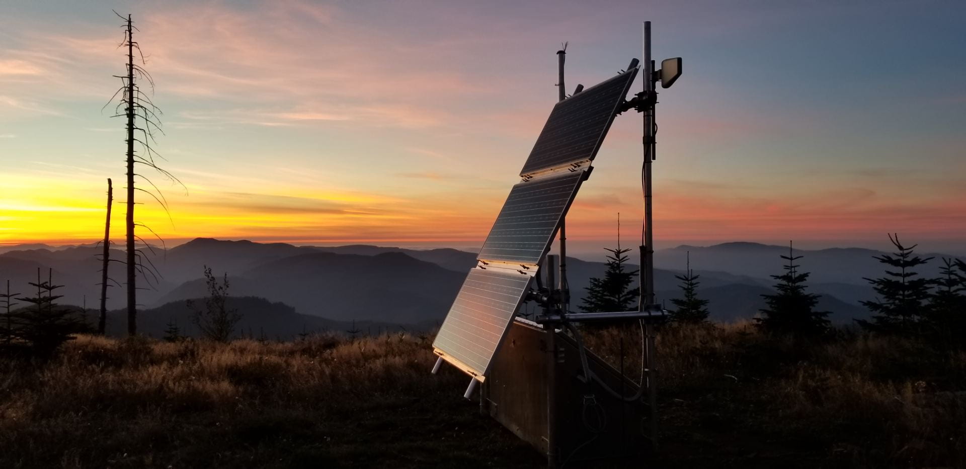 The sun sets behind a mountaintop seismic monitoring station.